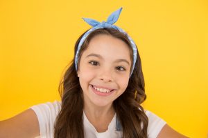 Smile like a model. Adorable small child with happy smile on yellow background. Happy little girl with healthy white smile on cheerful face. Enjoy brighter smile and whiter teeth.