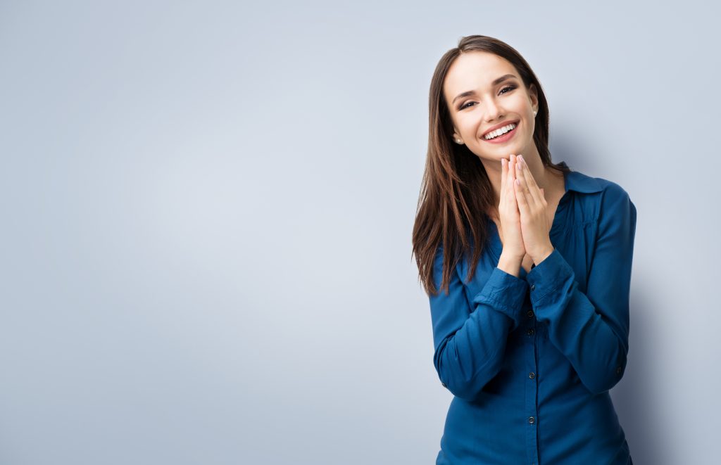 Portrait of happy gesturing smiling young woman in casual smart blue clothing, with copyspace for slogan or text message