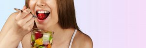 Young woman eating fruits from glass on