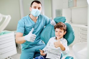 Happy dentist and child raised their thumb up at the dental clinic.