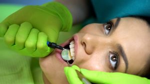 Dentist placing sealant on central incisor, cosmetic dentistry procedure, health